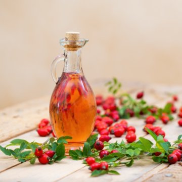Rosehip oil in bottle laid on wooden palette with copy space